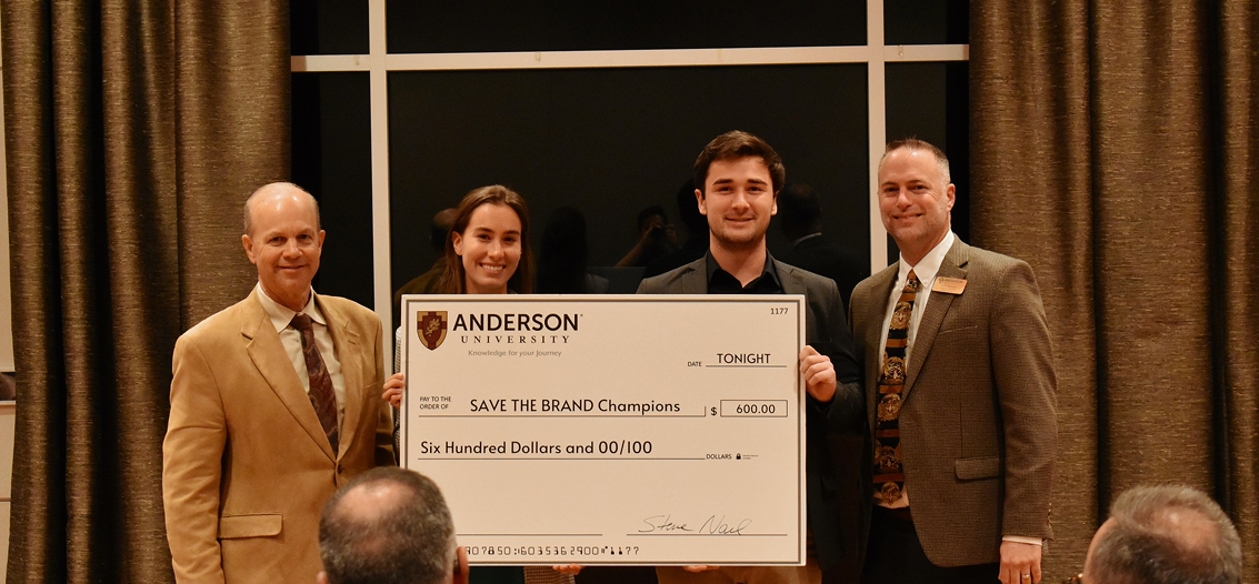 Two students holding a check for a scholarship.