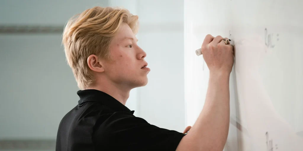 Student writing on a dry erase board