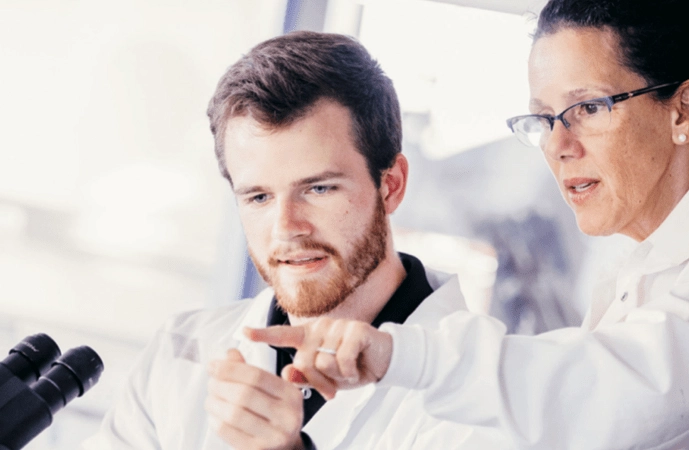 Two people in labcoats studying a microscope