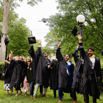 group of students in graduation attire throwing hats