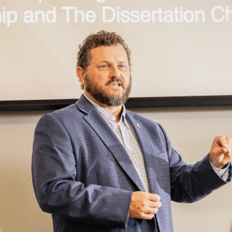 professor giving lecture in front of powerpoint presentation