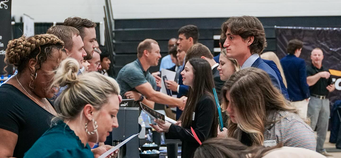 Students handing out their resumes to job recruiters.