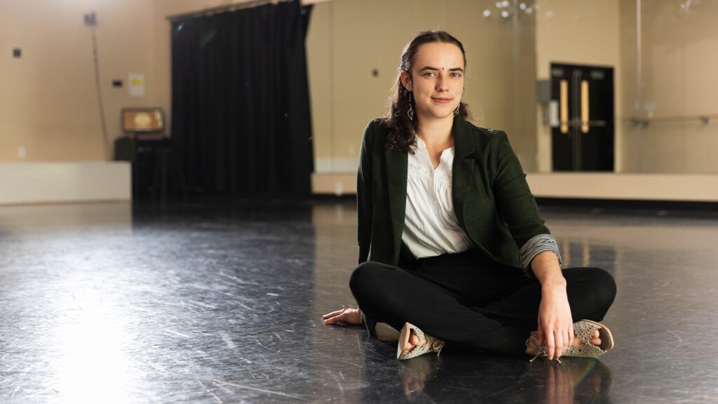 Anderson University dance student sitting on the floor of a dance studio.