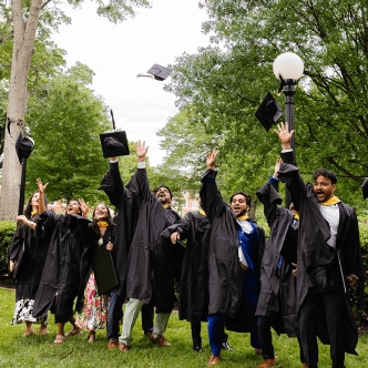group of students in graduation attire throwing hats