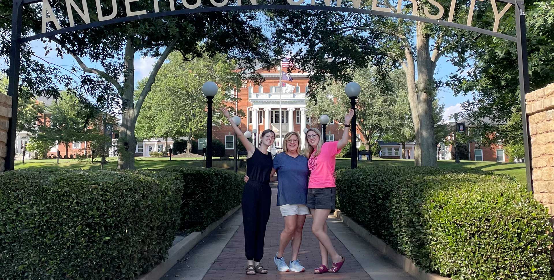 three ladies celebrating Move-In under the archway in front of Merritt