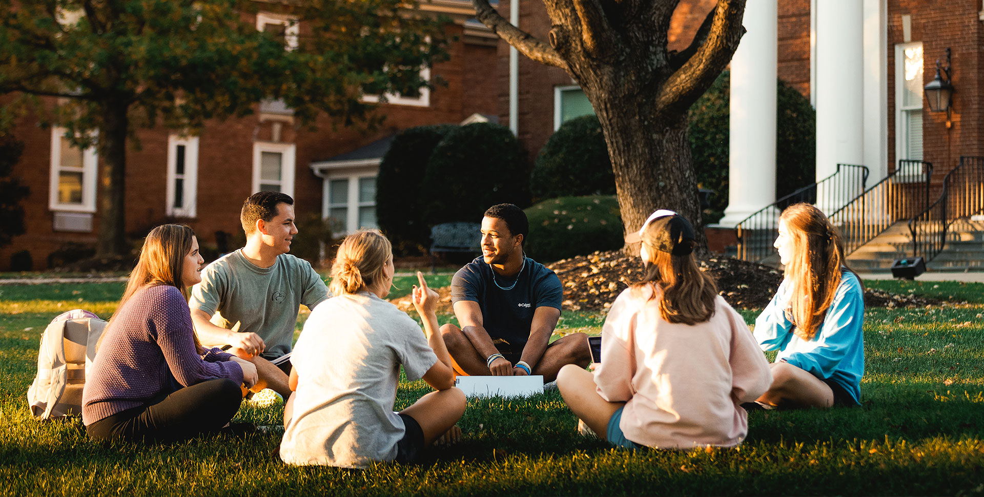 Alumni sitting in a circle on the front lawn