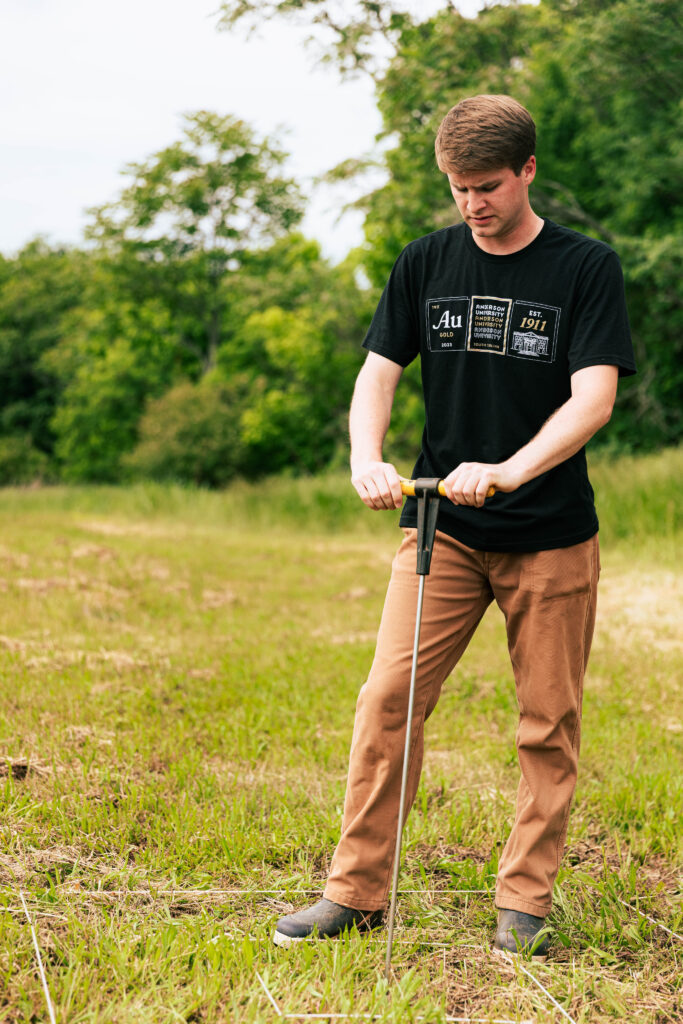 Anderson student, Reade Ward, standing outside using a soil sampler to collect soil for testing