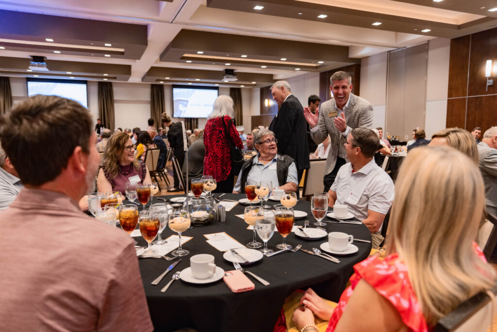 Dr. Bert Epting talking to a group of people sitting at a table at a Anderson University banquet